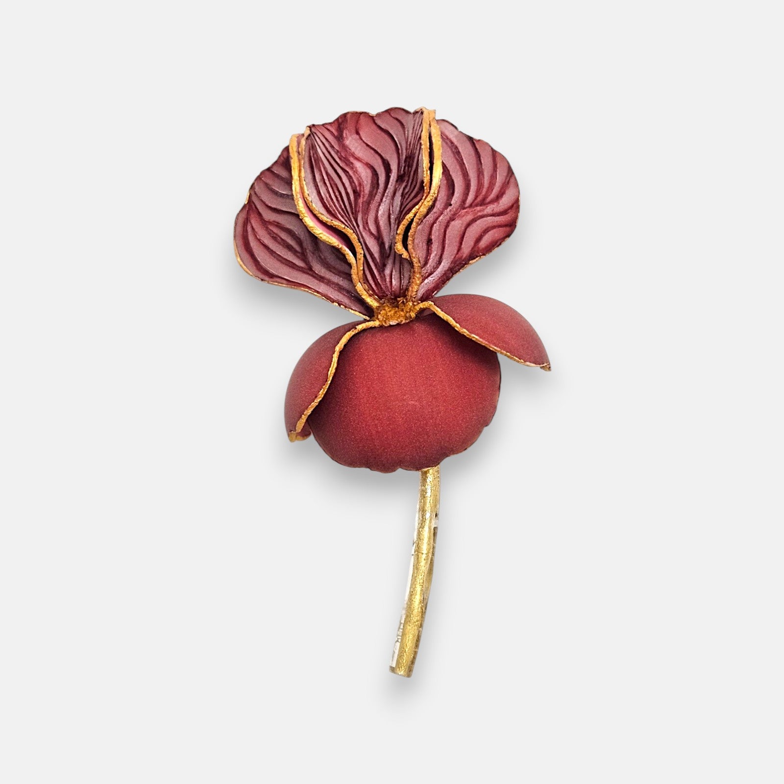 Broche maxi en forma de flor iris de Ciléa Paris, mostrando sus pétalos burdeos estriados con vetas doradas, base redonda granate mate y tallo de oro.