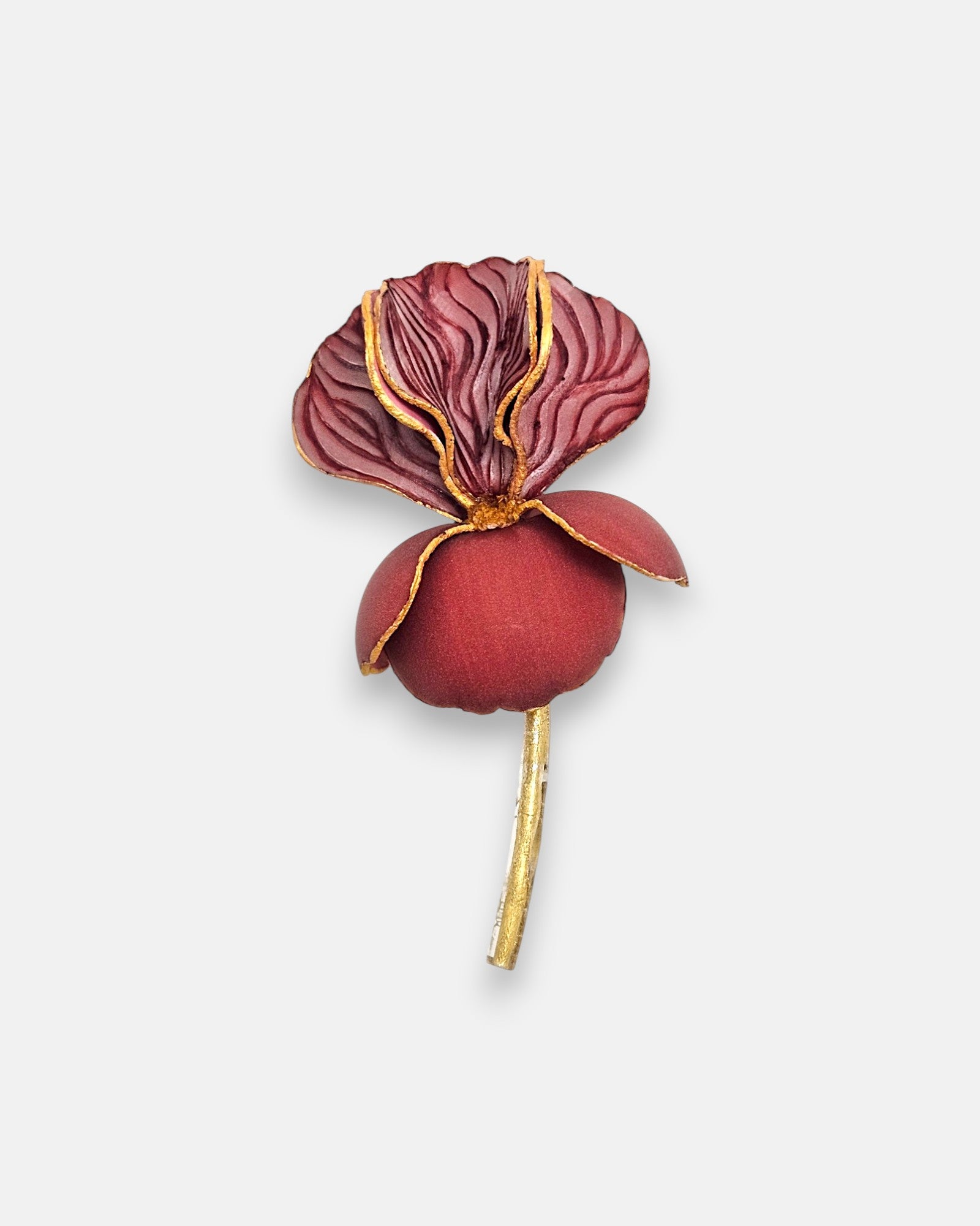 Broche maxi en forma de flor iris de Ciléa Paris, mostrando sus pétalos burdeos estriados con vetas doradas, base redonda granate mate y tallo de oro.