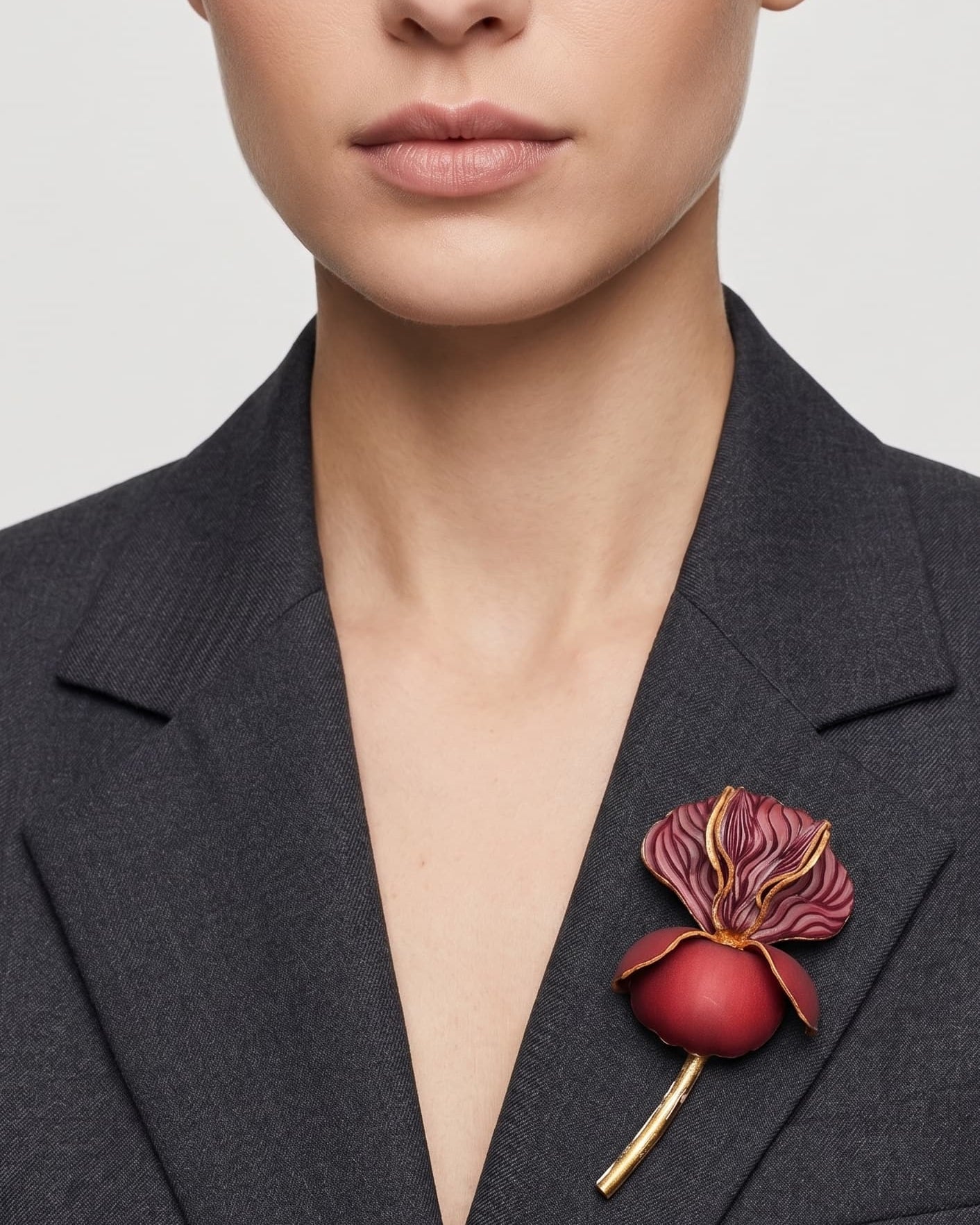 Vista frontal del maxibroche floral granate de Ciléa Paris prendido en la solapa de una chaqueta de traje gris oscura, detallando su volumen y relieve.