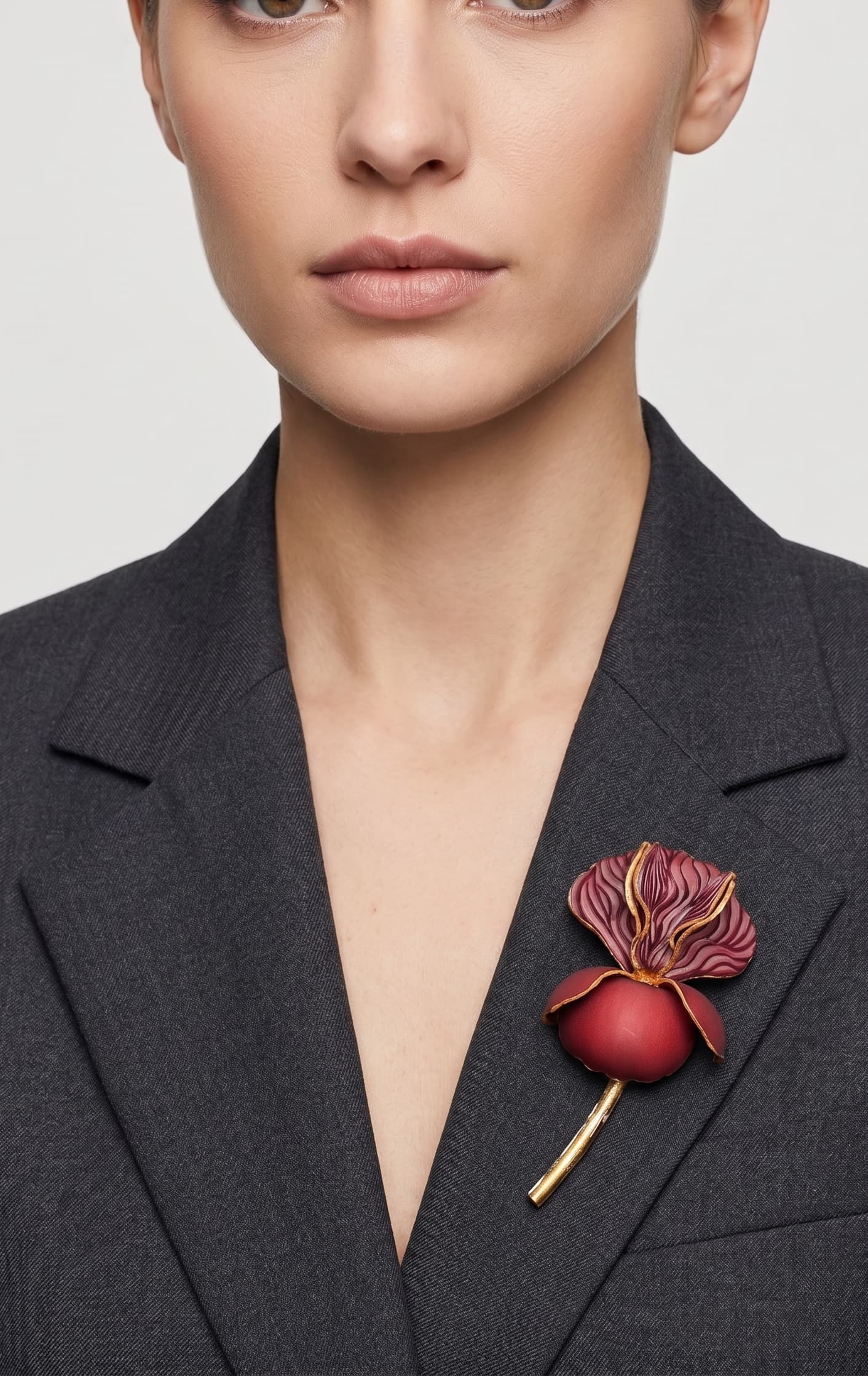 Vista frontal del maxibroche floral granate de Ciléa Paris prendido en la solapa de una chaqueta de traje gris oscura, detallando su volumen y relieve.