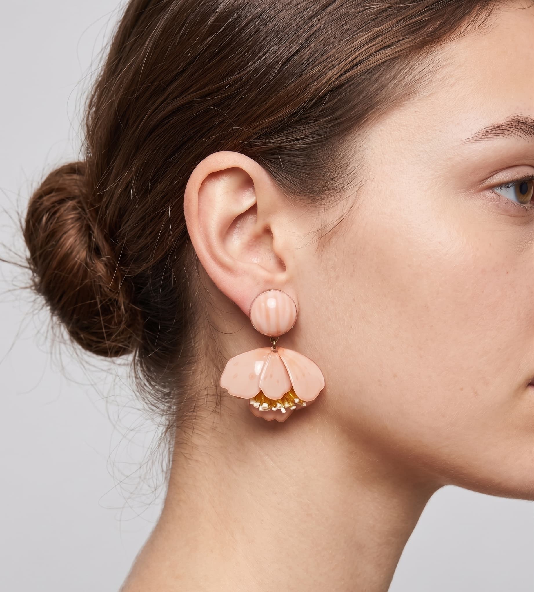 Vista de perfil de los pendientes colgantes de flor rosa de Ciléa Paris colocados en una modelo, detallando su caída y cómo asientan mediante su sistema de pinza.