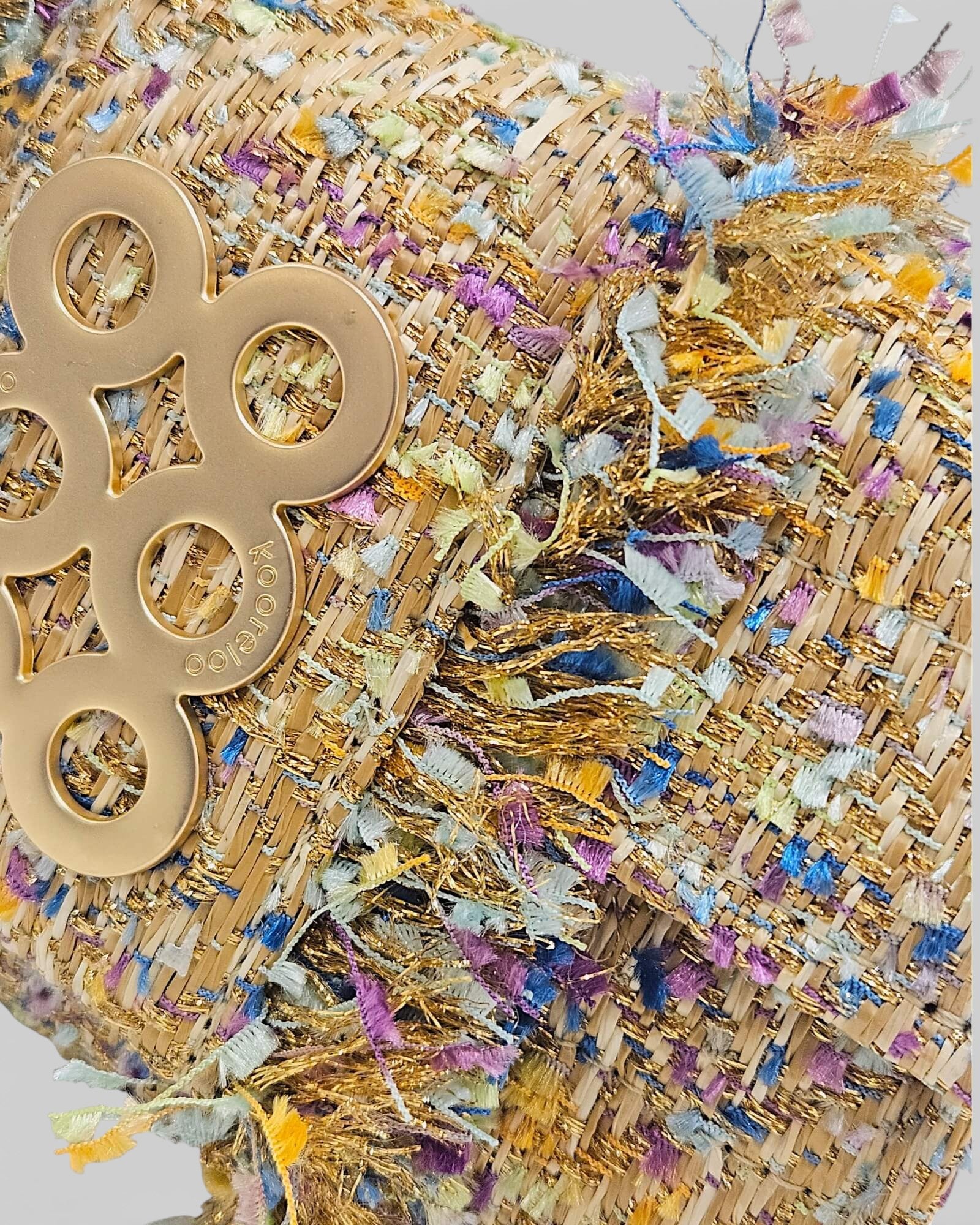 Primer plano de la textura del tejido tweed Kooreloo con hilos dorados, azules y púrpuras.