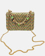 bolso de lino con diseño de zig-zag verde de Emanuela Caruso al completo, enseñando la caída de su bandolera larga de eslabones dorados sobre el fondo claro.