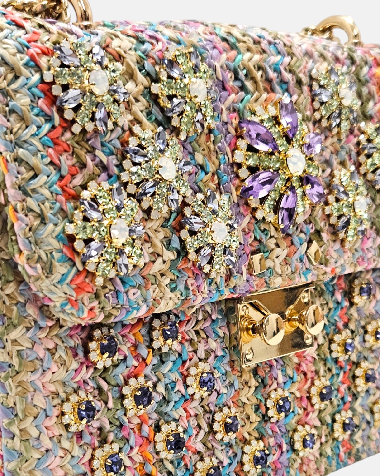 primer plano angular de la pedrería de Emanuela Caruso, revelando el relieve y la minuciosa disposición de las piedras de cristal facetadas en forma de flor y los pequeños apliques circulares inferiores.