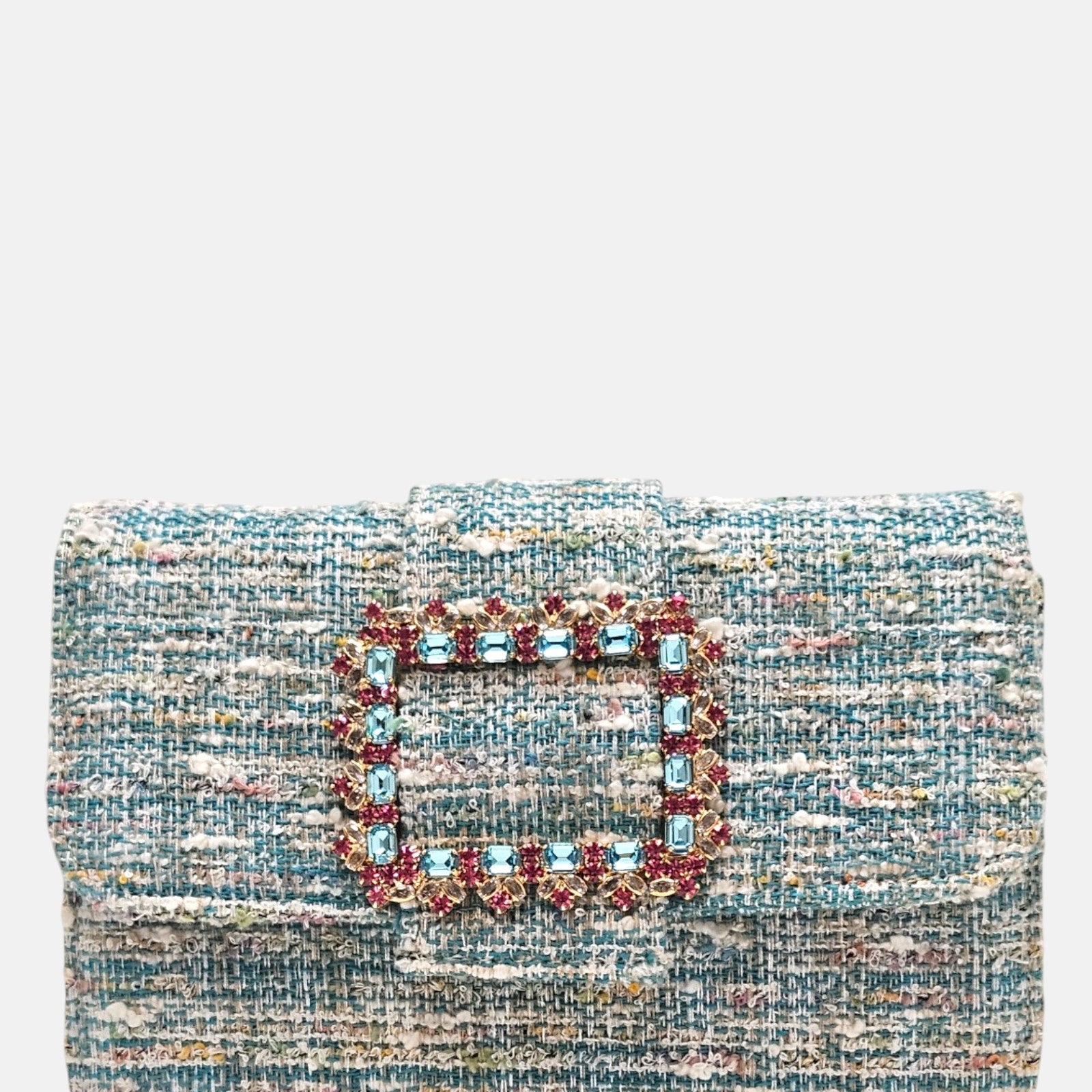 plano frontal de un bolso estructurado de Emanuela Caruso realizado en un elegante tejido jaspeado de tonos azules y verdes, resaltando una gran hebilla dorada central recubierta de piedras de cristal celestes y fucsias.