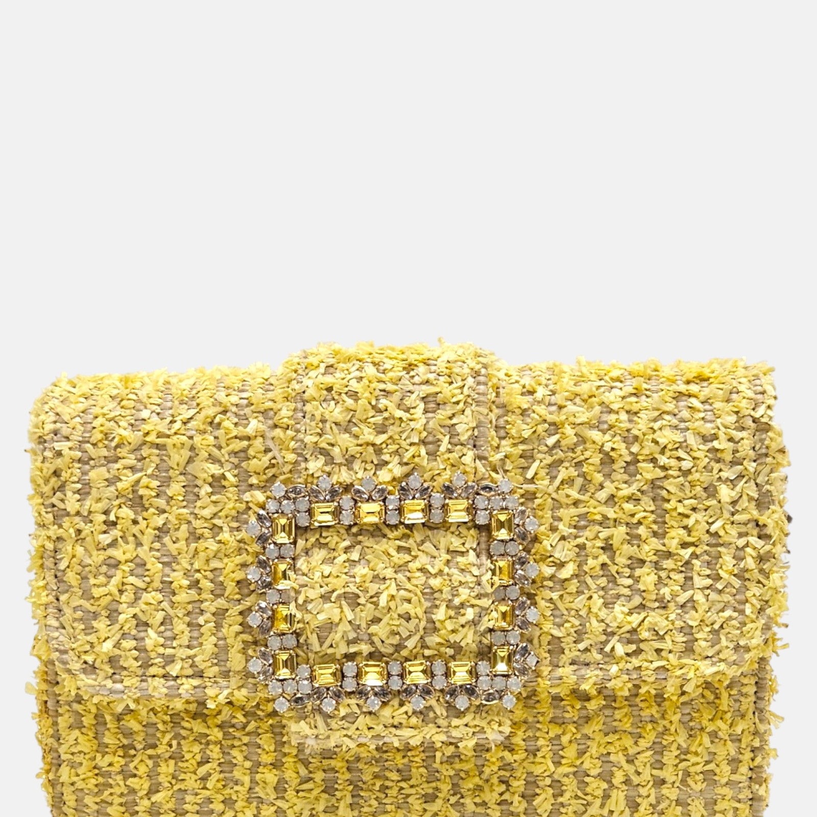 parte delantera de un bolso estructurado de Emanuela Caruso elaborado en un tejido texturizado, decorado con una gran hebilla dorada central recubierta de piedras de cristal claras y amarillas.
