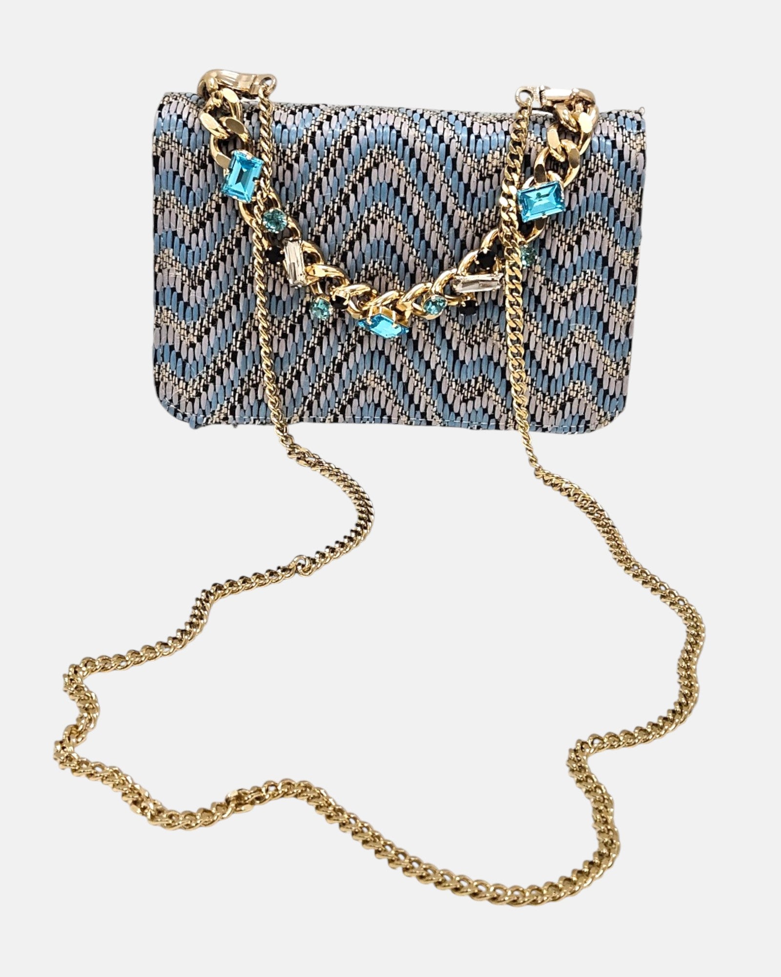 bolso textil con diseño de zig-zag de Emanuela Caruso al completo, enseñando la caída de su fina bandolera de eslabones dorados sobre un fondo claro.