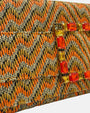 primer plano macro en ángulo del broche central, resaltando el minucioso engaste de las piedras de cristal rectangulares facetadas en tonos naranjas y dorados brillantes sobre el tejido de alta calidad.