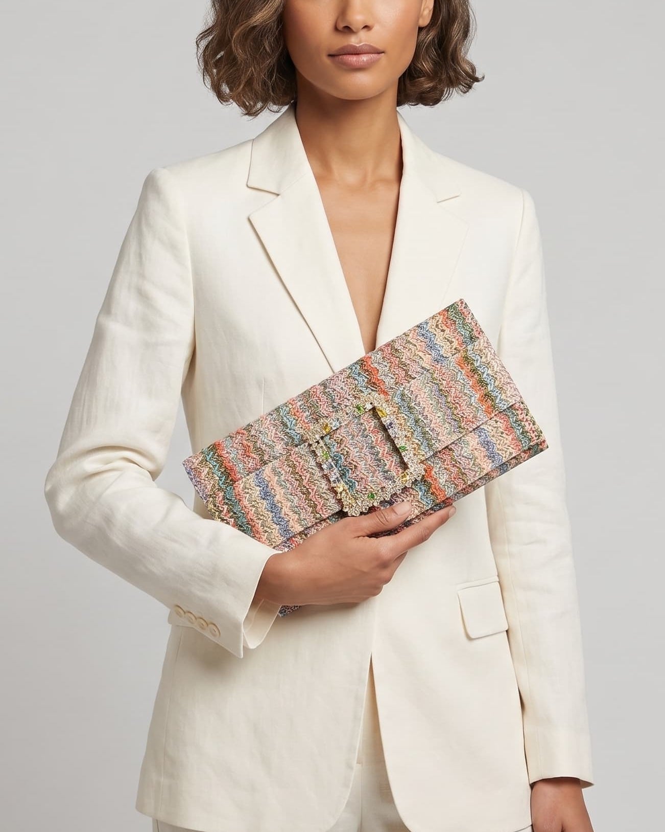 modelo posando con un traje de chaqueta blanco mientras sujeta la cartera de Emanuela Caruso con elegancia frente a ella.