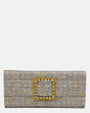 vista frontal de la cartera de mano tipo sobre de Emanuela Caruso realizada en un refinado tejido jaspeado lila, decorada con una gran hebilla cuadrada dorada con piedras de cristal claras y ámbar.
