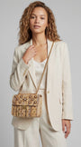 modelo con un traje de chaqueta color crema mientras lleva el bolso joya dorado de Emanuela Caruso colgado del hombro mediante su asa de cadena dorada.