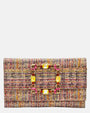 vista frontal de la cartera de mano tipo sobre de Emanuela Caruso con entramado textil multicolor y una gran hebilla rectangular dorada brillante cubierta de piedras de cristal de color amarillo y rosa.