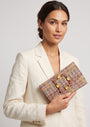 modelo posando con una chaqueta blanca mientras sujeta la cartera de Emanuela Caruso con elegancia hacia un lado.