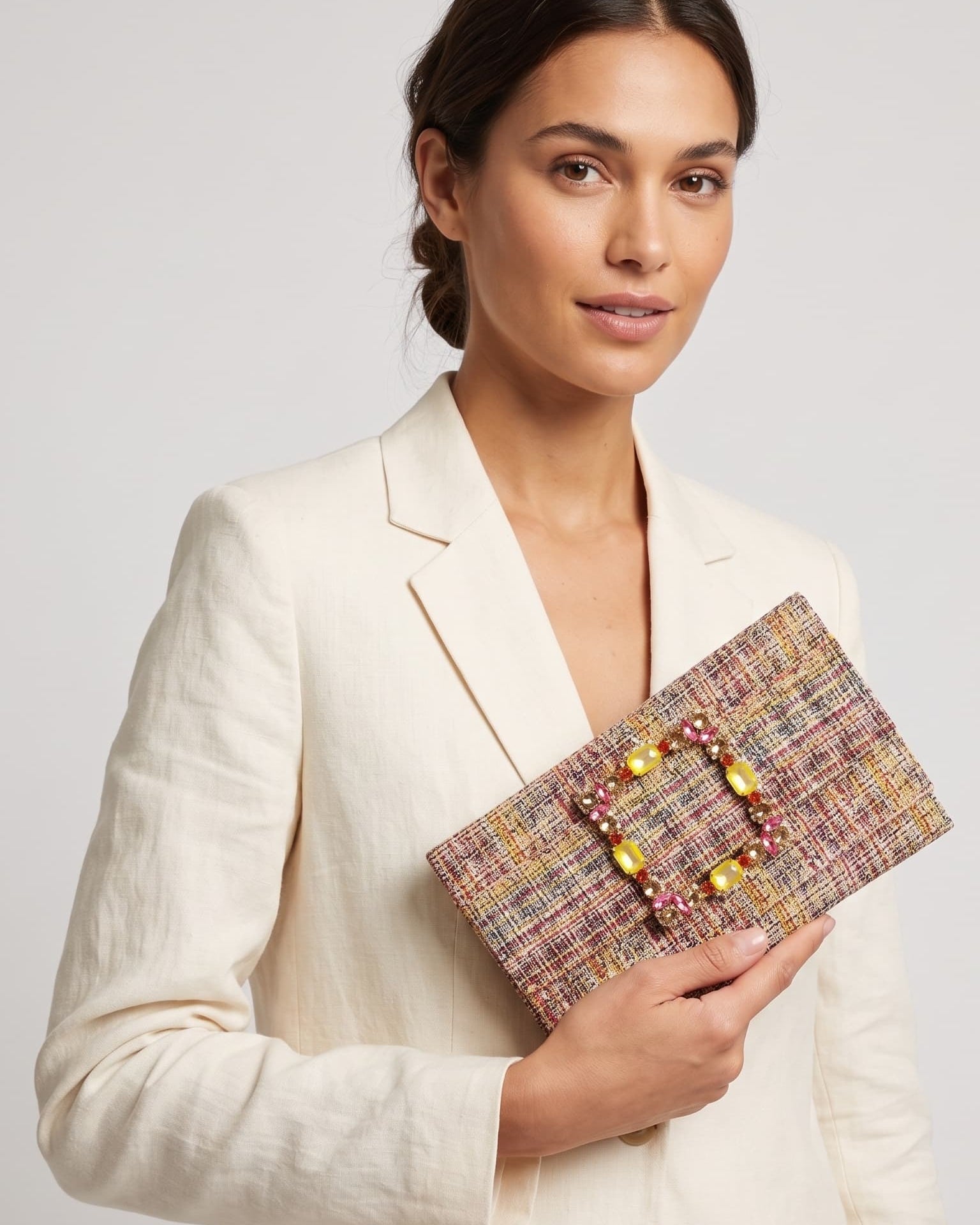 modelo posando con una chaqueta blanca mientras sujeta la cartera de Emanuela Caruso con elegancia hacia un lado.