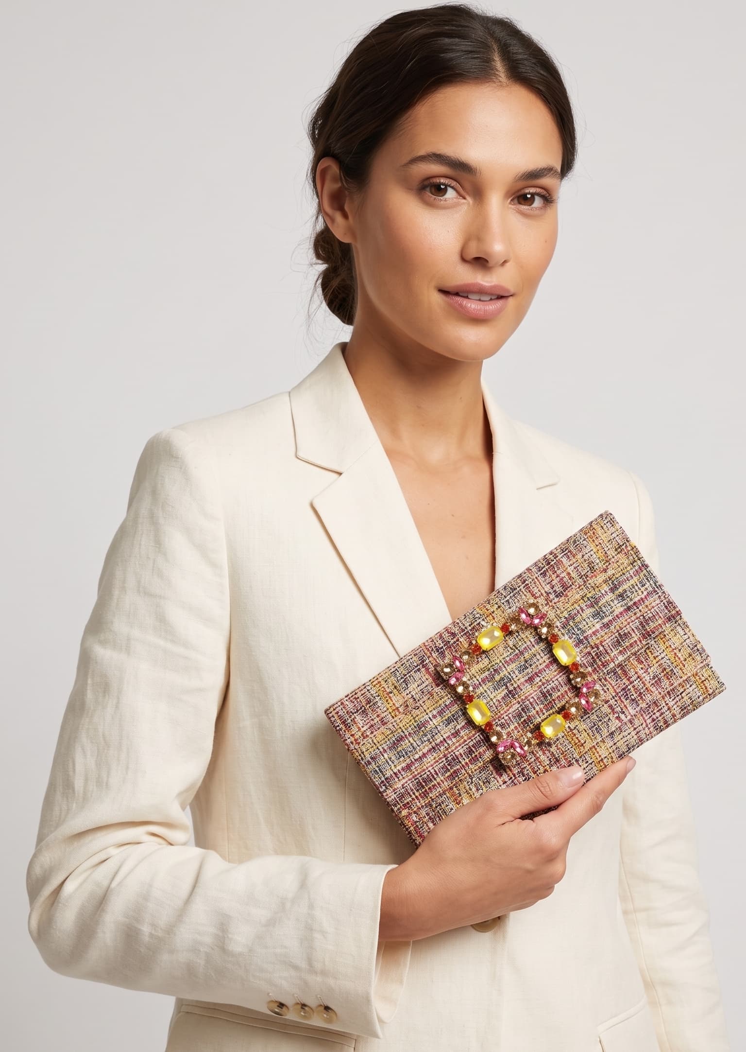 modelo posando con una chaqueta blanca mientras sujeta la cartera de Emanuela Caruso con elegancia hacia un lado.