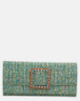 vista frontal de la cartera de mano tipo sobre de Emanuela Caruso realizada en un refinado tejido jaspeado turquesa, decorada con una gran hebilla cuadrada dorada con piedras de cristal celestes y fucsias.