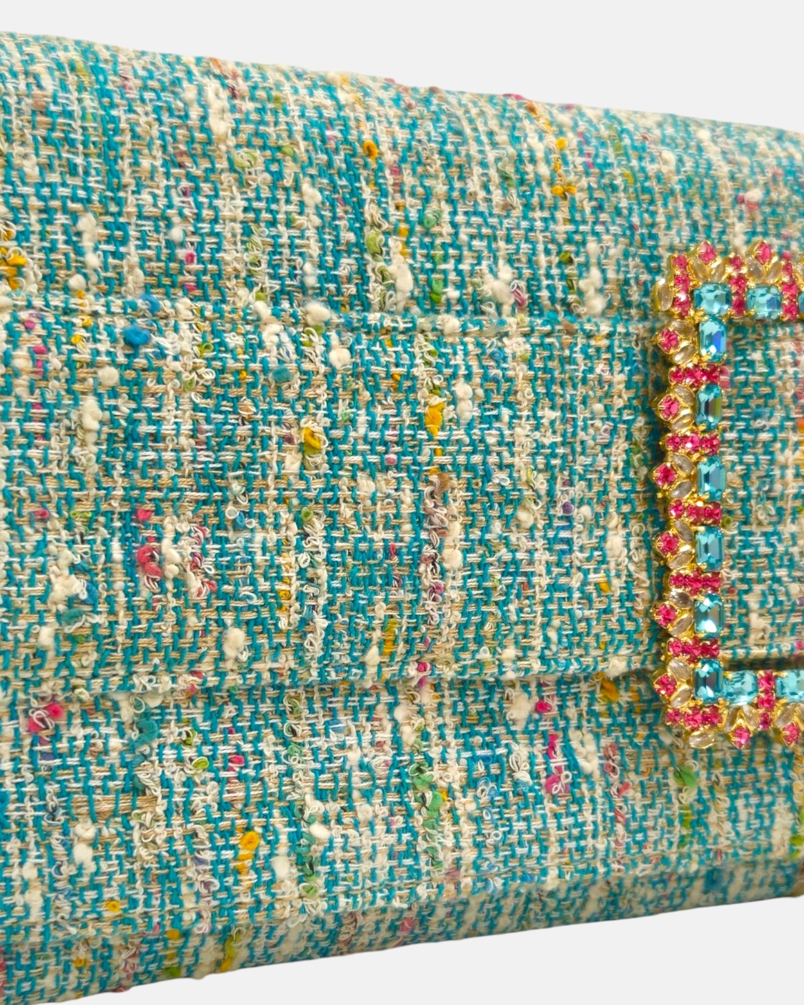 primer plano angular de la solapa, destacando la textura del tejido textil premium turquesa y el minucioso engaste de las piedras de cristal rectangulares celestes y fucsias de la hebilla.
