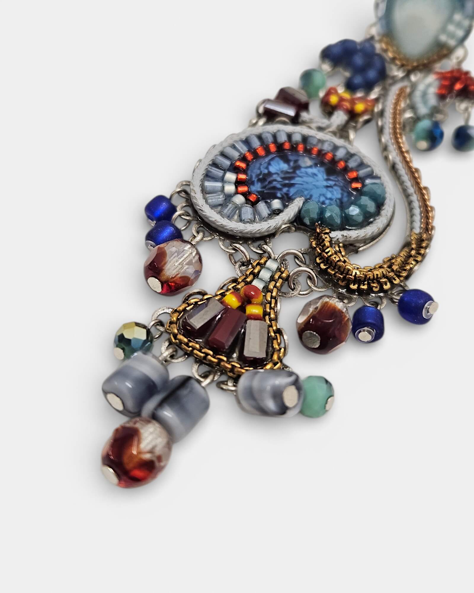 Primer plano de la pedrería y el diseño floral del pendiente Estival, mostrando la calidad de los cristales y el bordado.