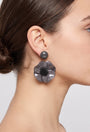 Vista de perfil de los pendientes colgantes de mariposa de Ciléa Paris colocados en una modelo, detallando su volumen maxi y cómo asientan con su cómodo sistema de pinza.