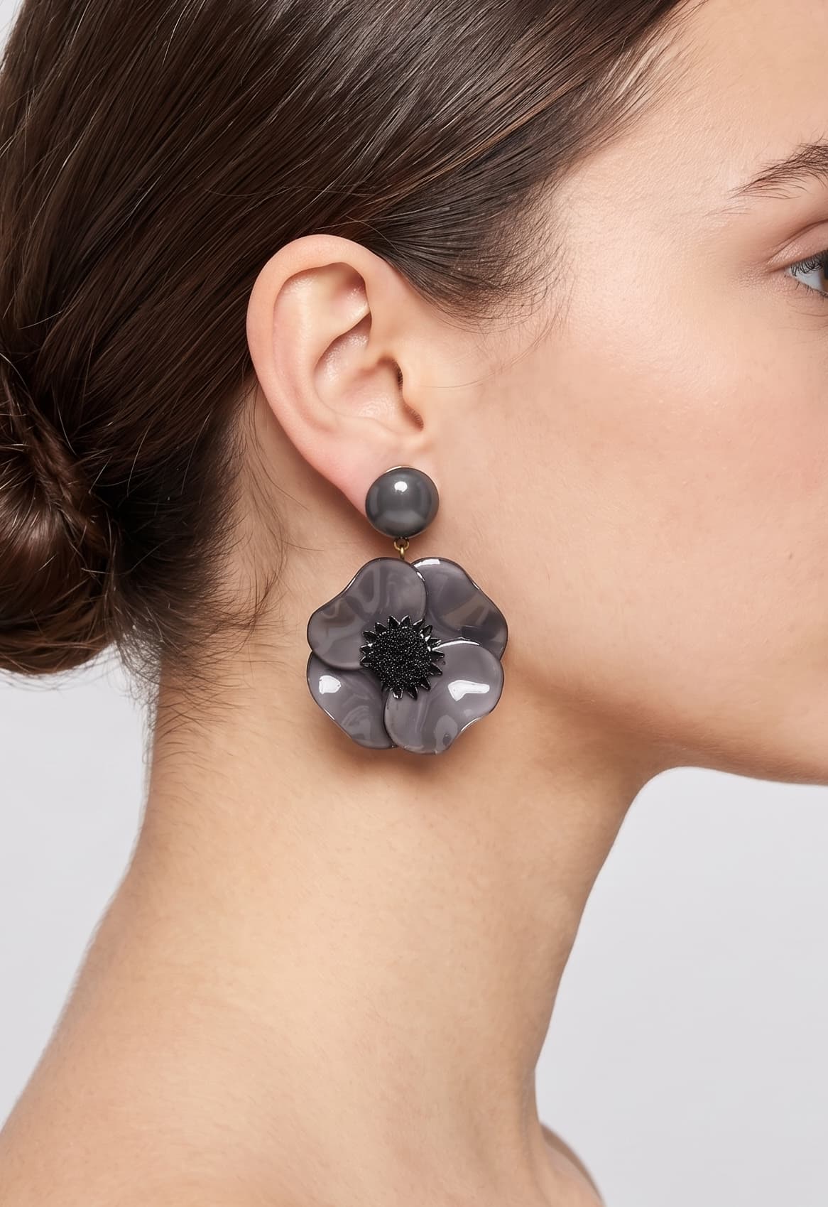 Vista de perfil de los pendientes colgantes de mariposa de Ciléa Paris colocados en una modelo, detallando su volumen maxi y cómo asientan con su cómodo sistema de pinza.