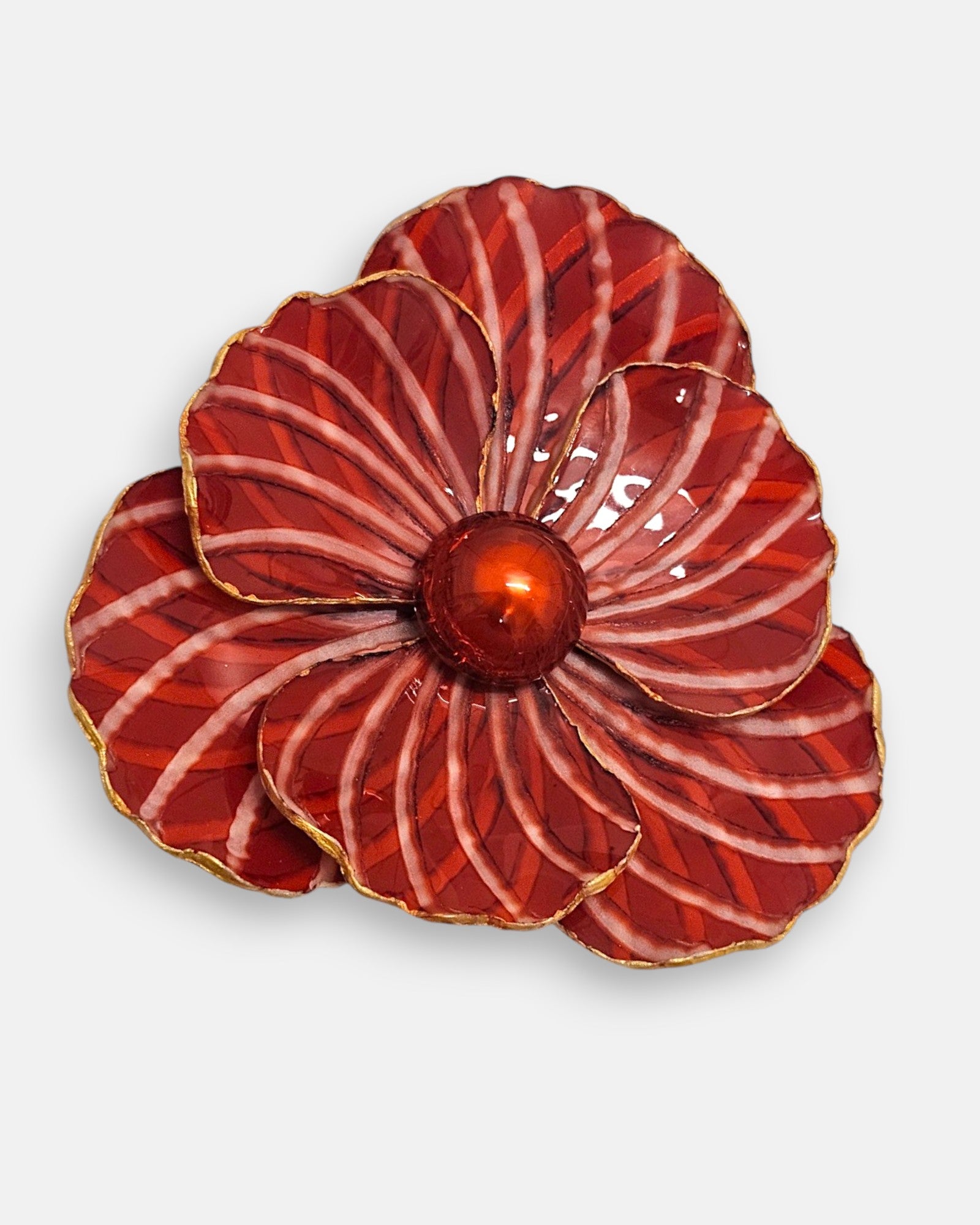Primer plano macro de la flor artesanal de Ciléa Paris, detallando el patrón de líneas estriadas crema sobre el fondo rojo brillante y la cúpula central esférica.