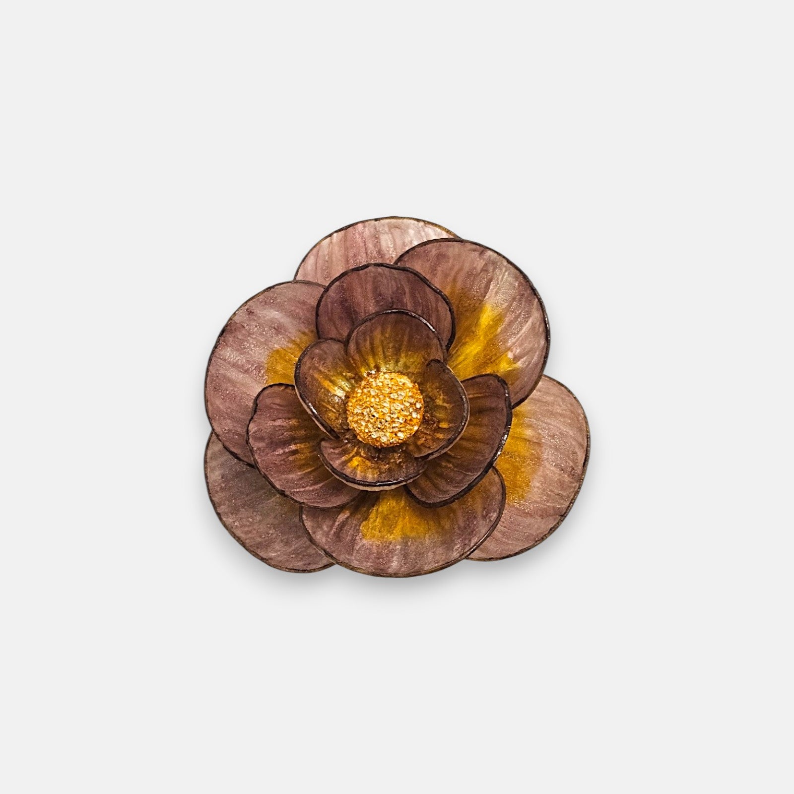 Broche redondo en forma de flor camelia de Ciléa Paris, mostrando sus pétalos superpuestos en color malva con vetas de oro viejo y centro rugoso dorado.