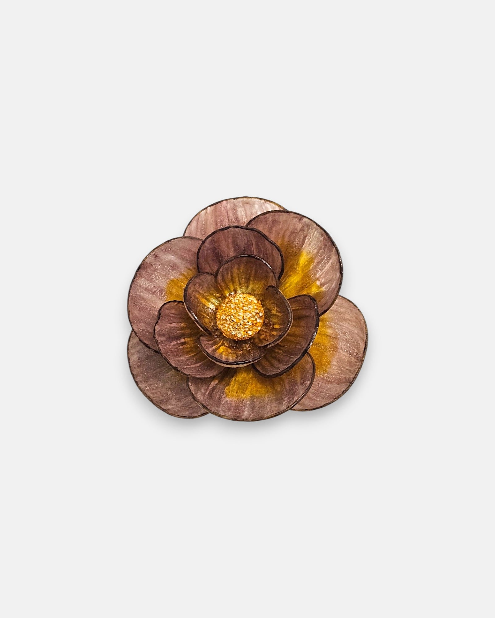 Broche redondo en forma de flor camelia de Ciléa Paris, mostrando sus pétalos superpuestos en color malva con vetas de oro viejo y centro rugoso dorado.