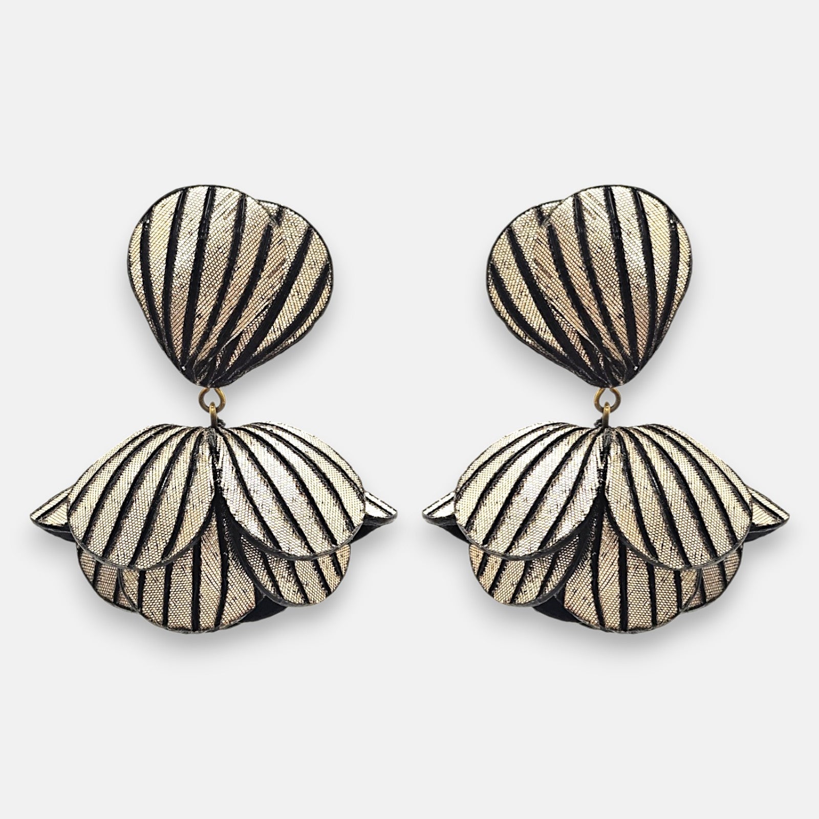 Pareja de pendientes grandes en forma de flor abstracta de Ciléa Paris, mostrando sus pétalos oro champaña texturizados con rayas negras verticales.