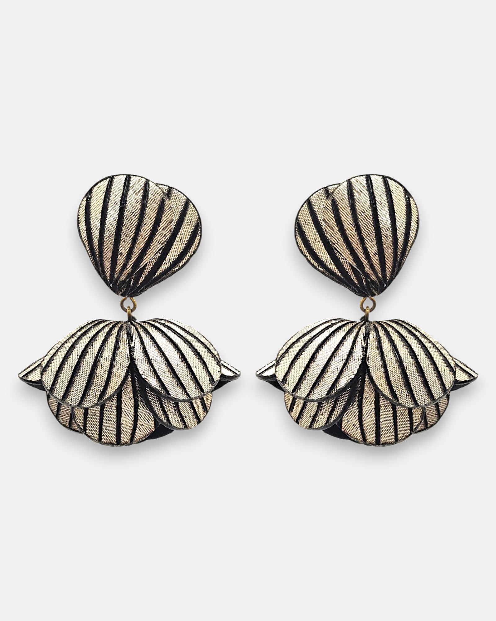 Pareja de pendientes grandes en forma de flor abstracta de Ciléa Paris, mostrando sus pétalos oro champaña texturizados con rayas negras verticales.