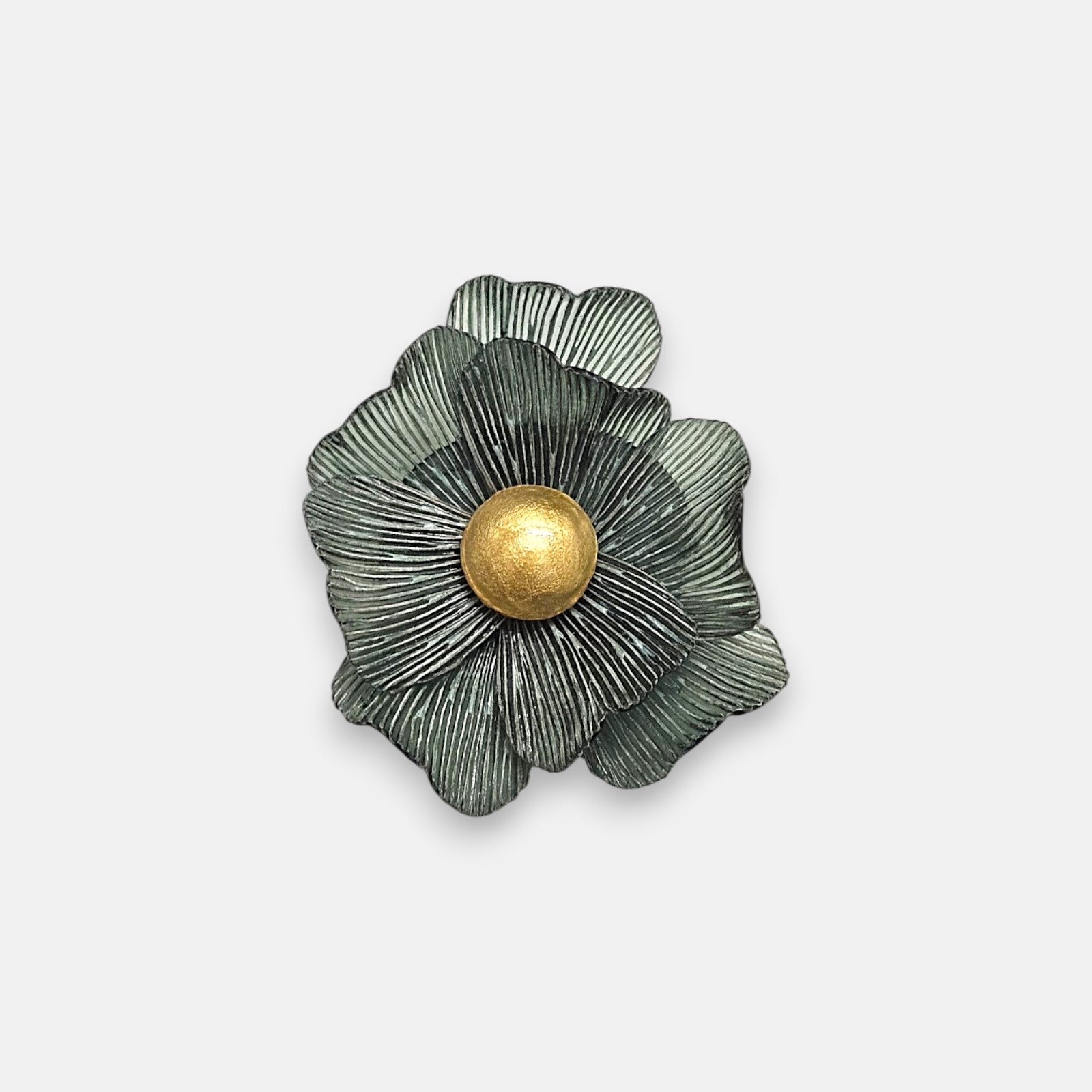 Broche mediano en forma de flor camelia de Ciléa Paris, mostrando sus pétalos verde musgo estriados y su gran botón central esférico en oro viejo.