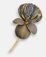 Primer plano macro de la flor artesanal de Ciléa Paris, detallando el labrado texturizado de los pétalos gris grafito y los perfiles metalizados en oro viejo.