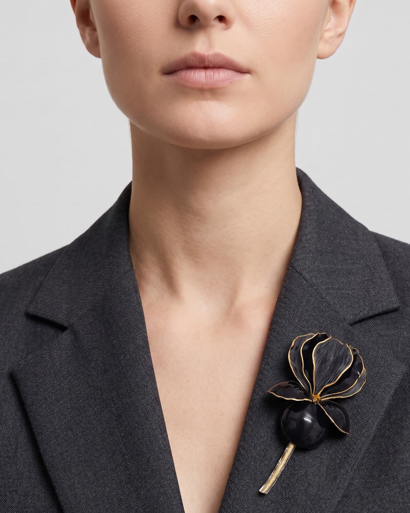 Vista frontal del maxibroche floral negro de Ciléa Paris prendido en la solapa de una chaqueta de traje gris, detallando su volumen y relieve tridimensional.