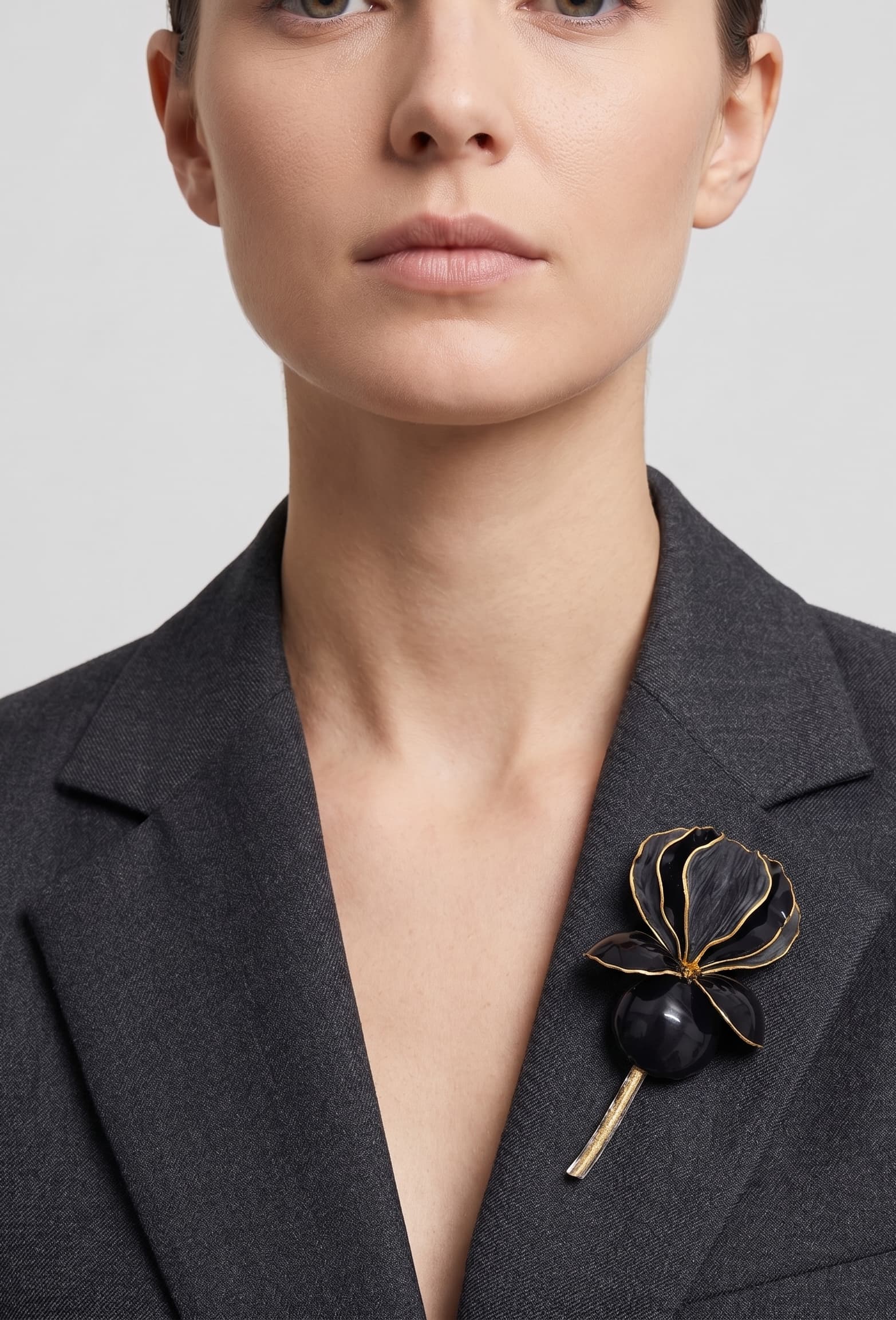 Vista frontal del maxibroche floral negro de Ciléa Paris prendido en la solapa de una chaqueta de traje gris, detallando su volumen y relieve tridimensional.