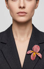 Vista frontal del broche floral rosa de Ciléa Paris prendido en la solapa de una chaqueta de traje gris oscura, detallando su volumen y relieve tridimensional.