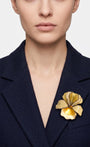 Vista frontal del broche floral crema de Ciléa Paris prendido en la solapa de una americana de traje azul marino, detallando su relieve tridimensional.