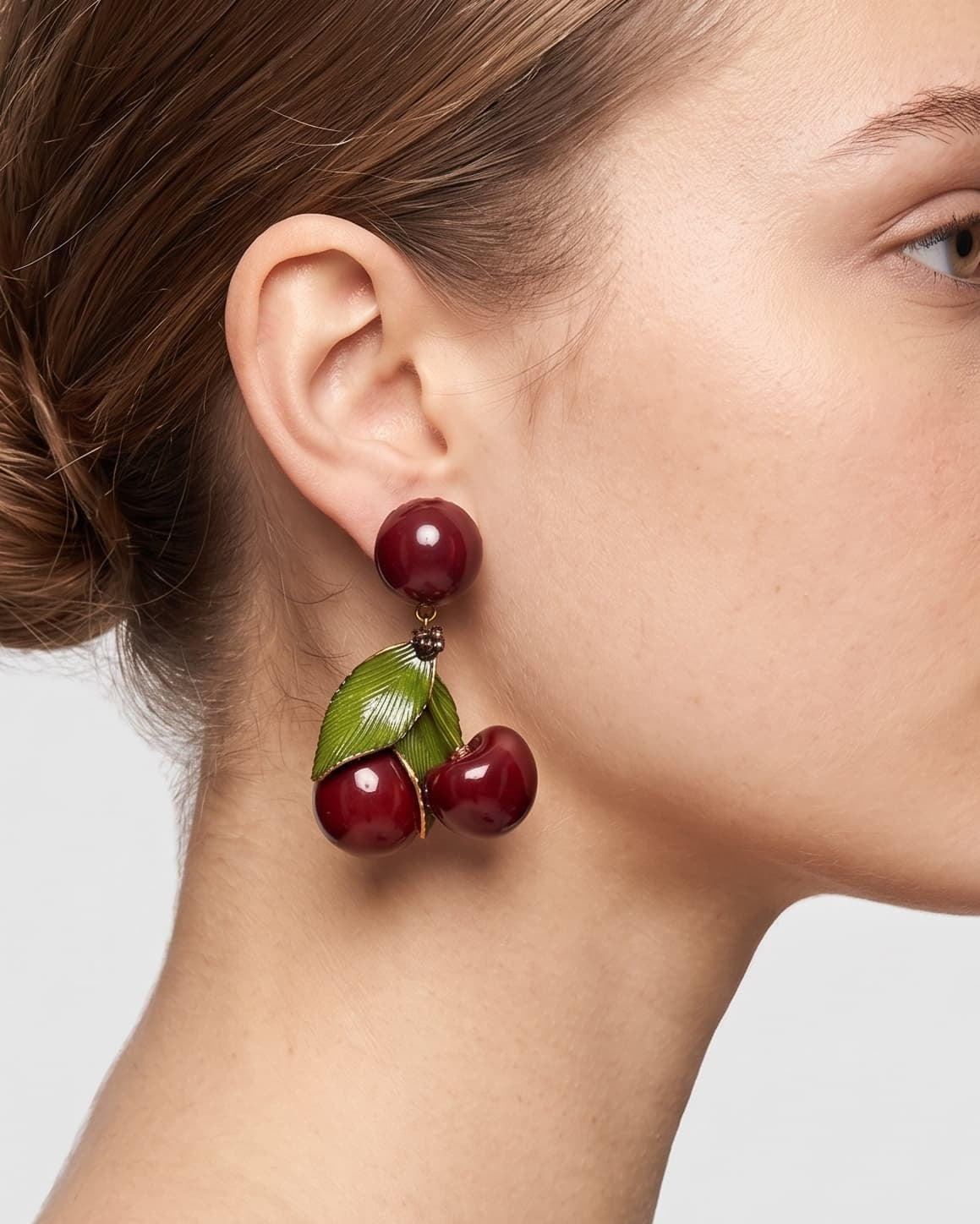 Vista de perfil de los maxipendientes colgantes de cerezas de Ciléa Paris colocados en una modelo, detallando su volumen brillante y su cómodo sistema de pinza.