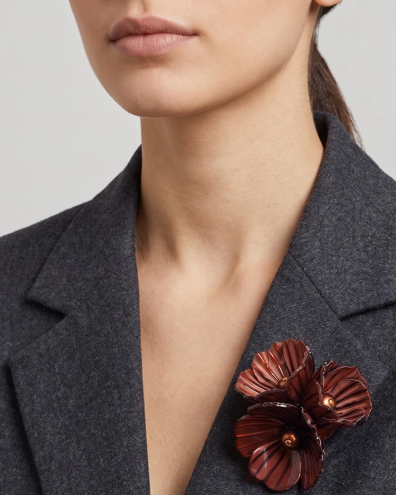 Vista frontal del broche Bouquet Châtaigne de Ciléa Paris prendido en la solapa de una chaqueta de traje gris, detallando su relieve tridimensional.