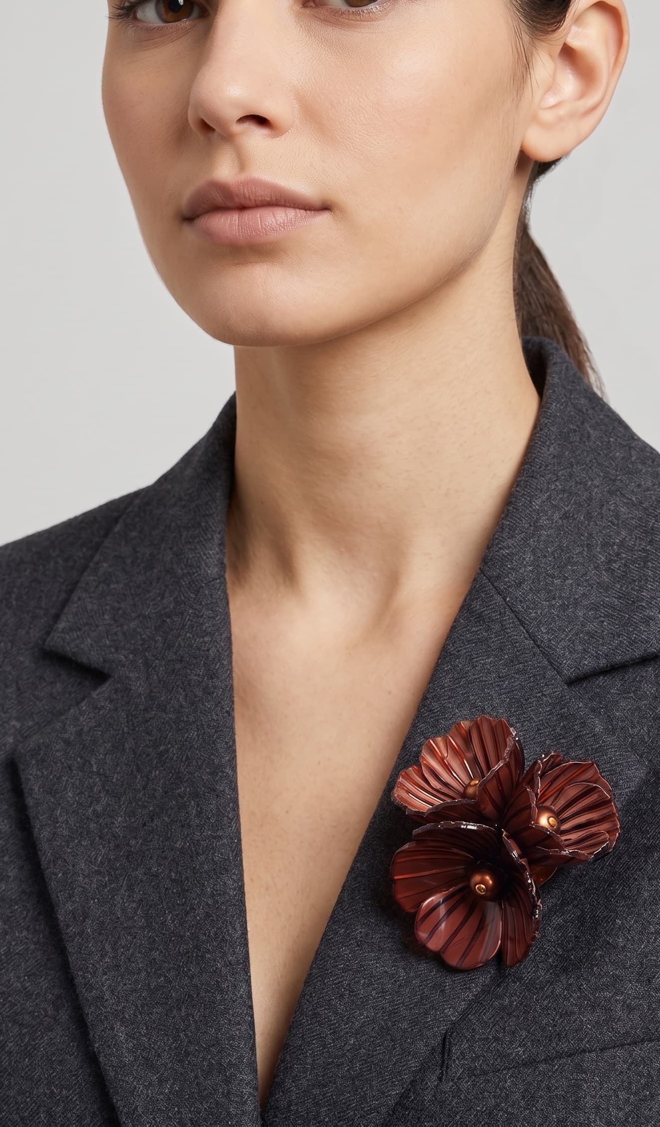 Vista frontal del broche Bouquet Châtaigne de Ciléa Paris prendido en la solapa de una chaqueta de traje gris, detallando su relieve tridimensional.