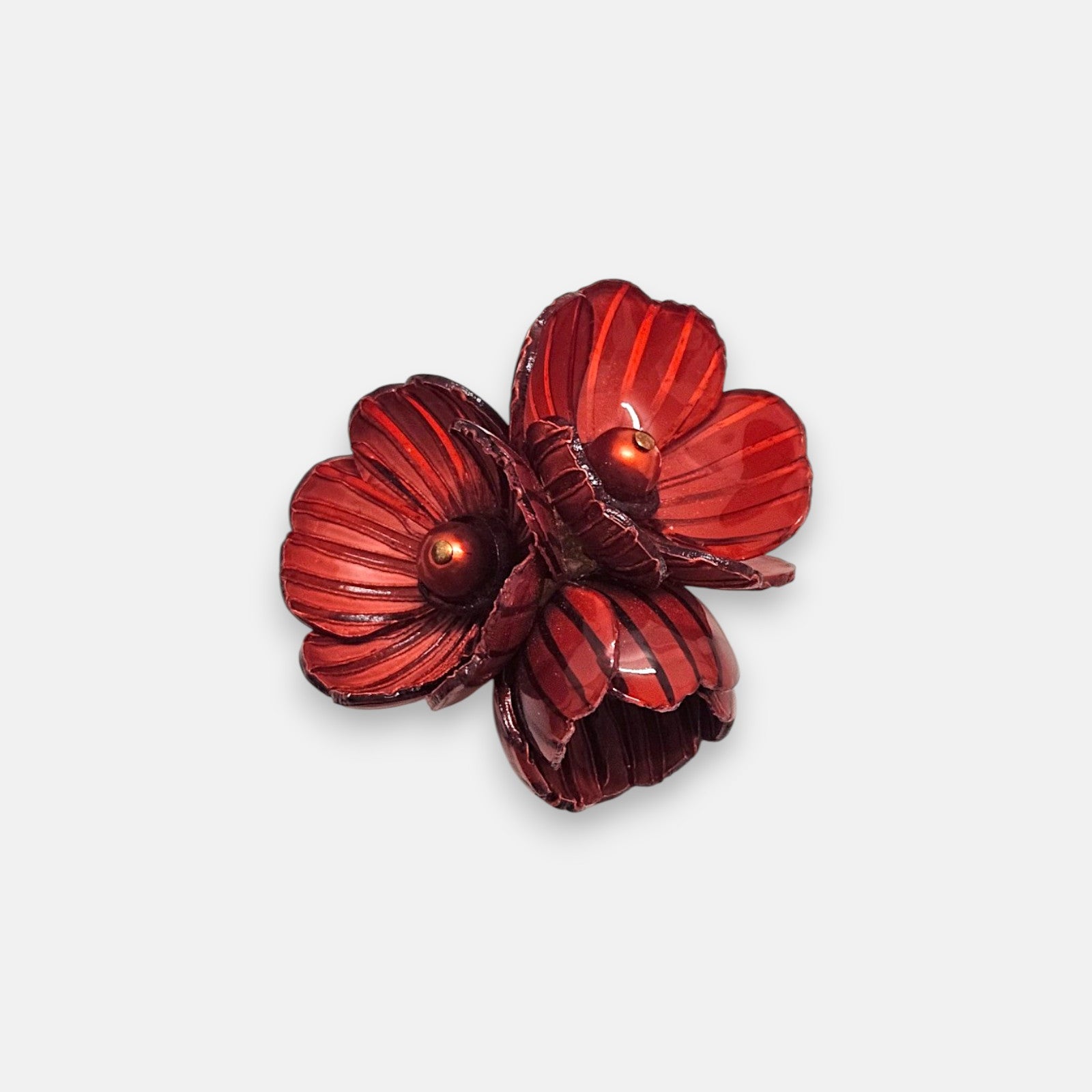 Broche mediano de Ciléa Paris en forma de ramillete de tres flores en color rojo borgoña esmaltado con líneas oscuras y centros redondos metalizados.