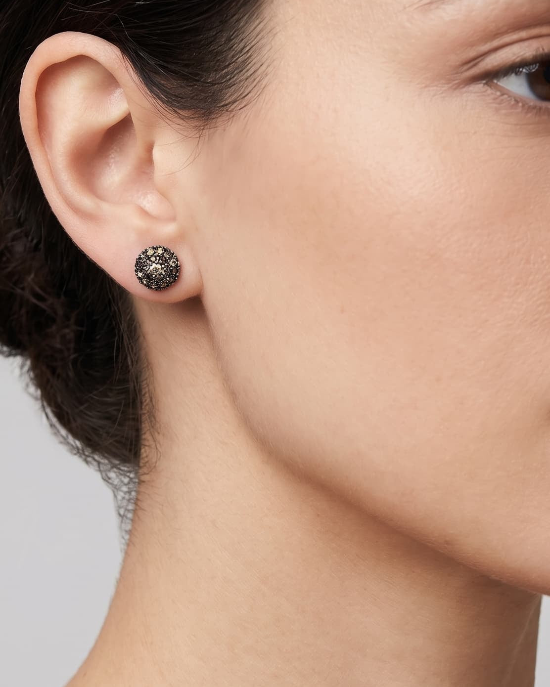 Mujer luciendo los pendientes de botón champagne de Bohemme, resaltando su brillo cálido y elegante en el lóbulo.