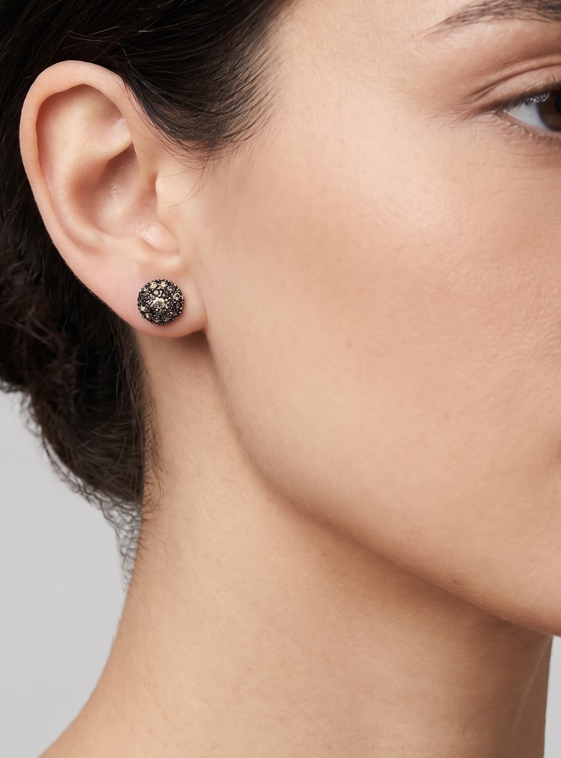 Mujer luciendo los pendientes de botón champagne de Bohemme, resaltando su brillo cálido y elegante en el lóbulo.