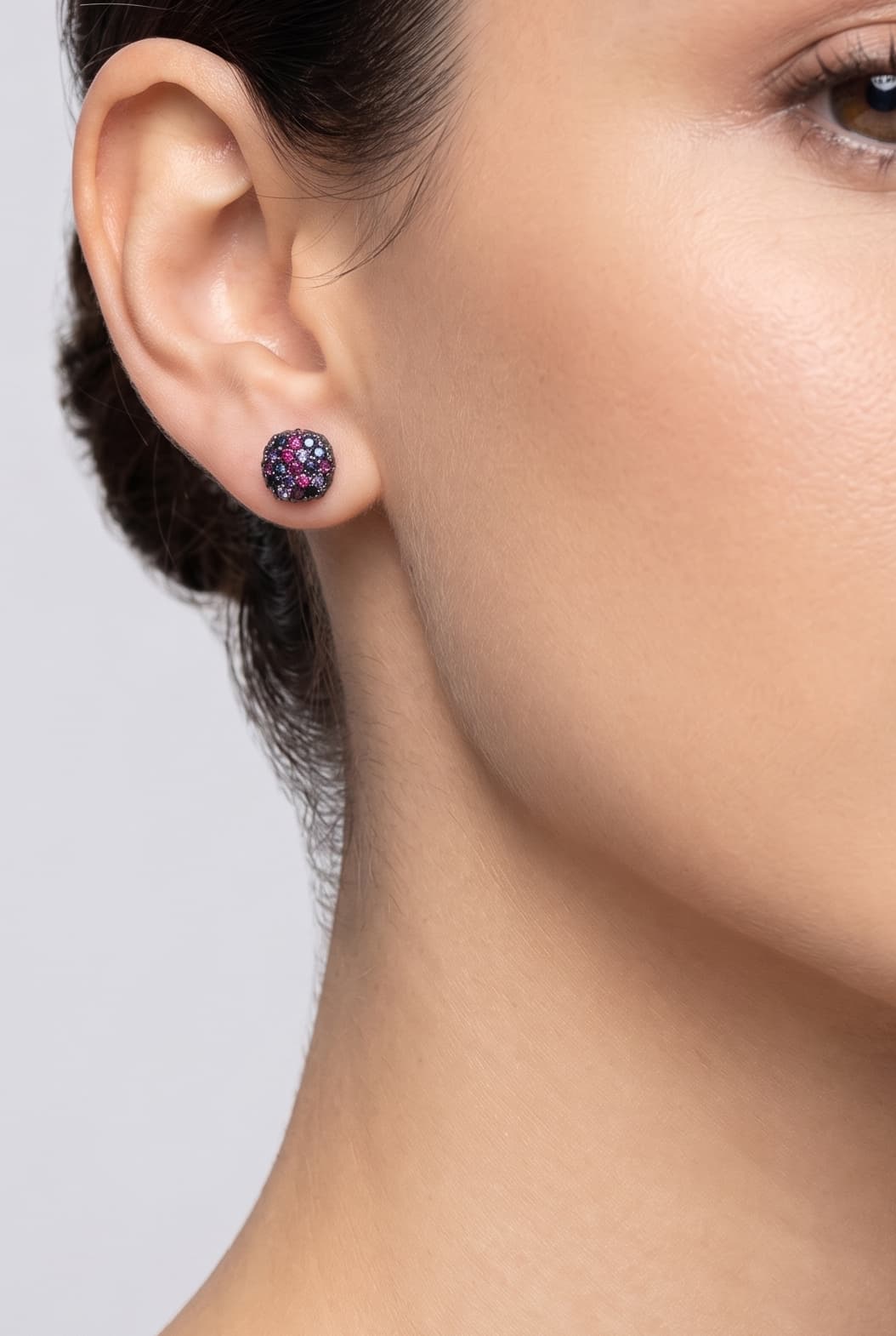 Mujer luciendo los pendientes de botón Iris Mosaic de Bohemme, resaltando su brillo vibrante y ajuste perfecto al lóbulo.