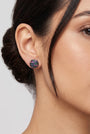 Mujer luciendo los pendientes de botón negros Obsidian Dot de Bohemme, resaltando su brillo discreto y ajuste al lóbulo.