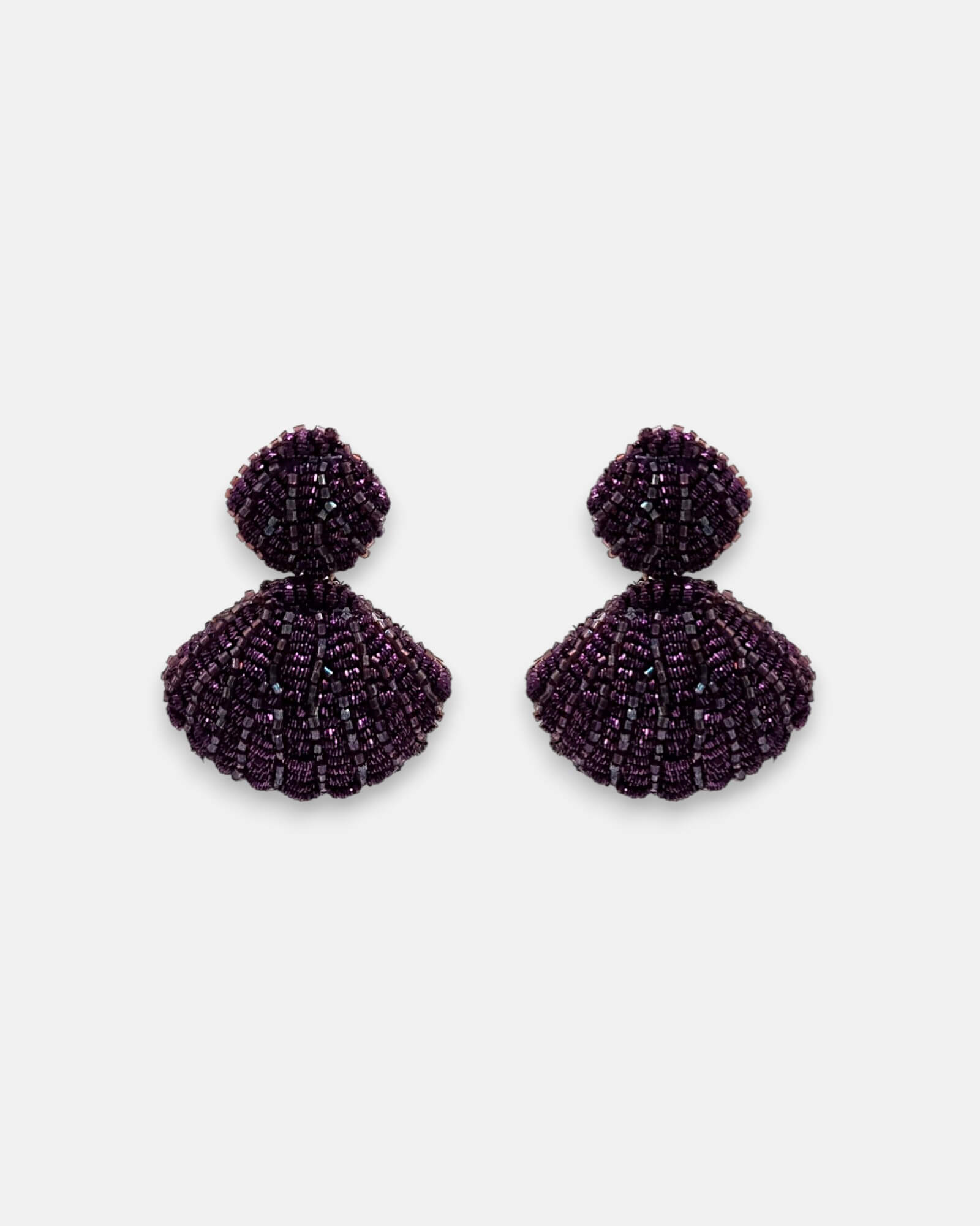 Pendientes "Noche de Cristal" en tono amatista con acabado tejido y diseño de concha sobre fondo claro.