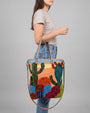 Mujer luciendo el bolso "Horizonte Silvestre" al hombro, destacando su tamaño funcional y diseño colorido
