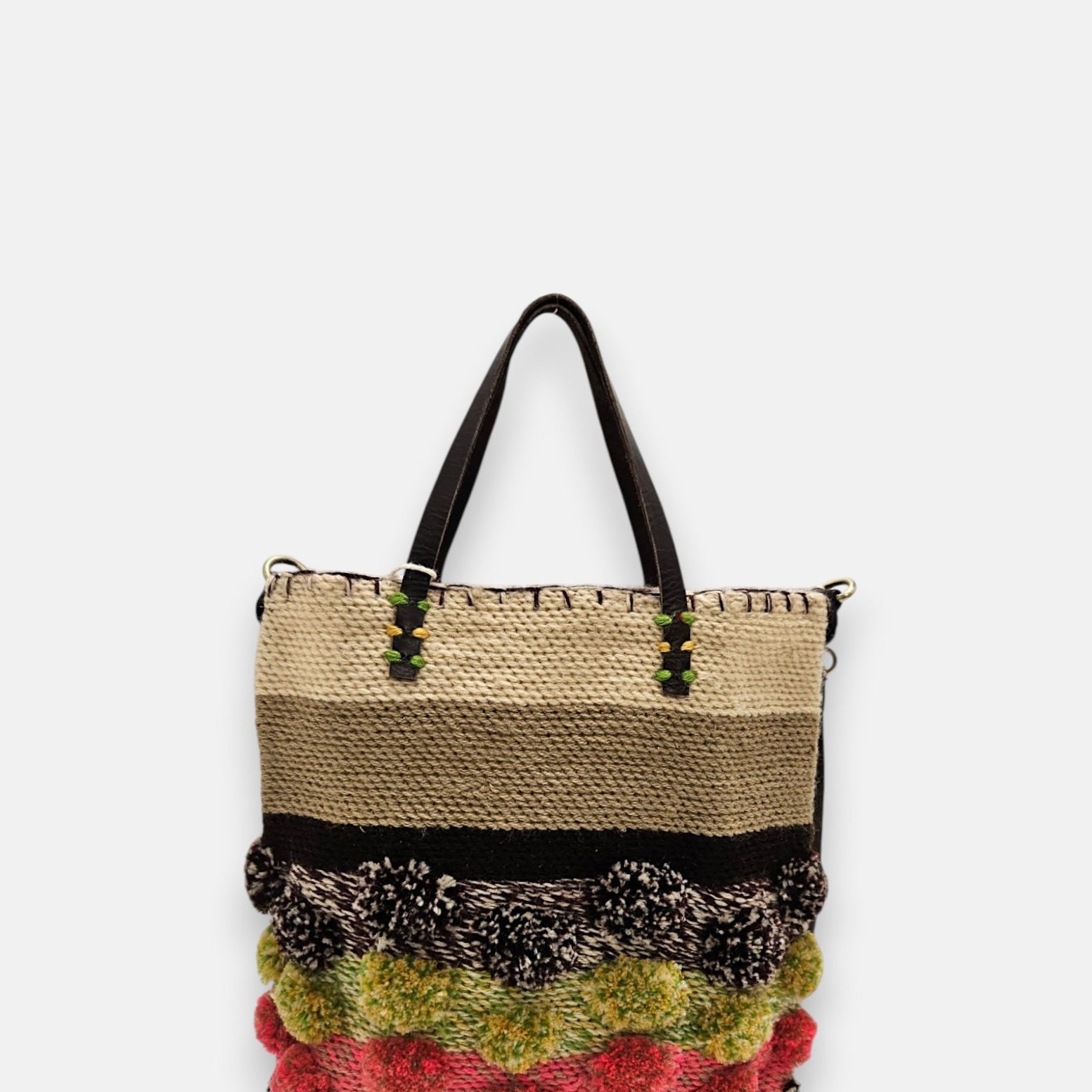 Bolso pequeño de rafia con bandas de colores tierra, verde y rosa con pompones artesanales.