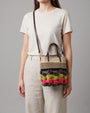 Mujer luciendo el bolso XS "Jardín de Invierno" como bandolera, destacando su tamaño compacto y diseño colorido.