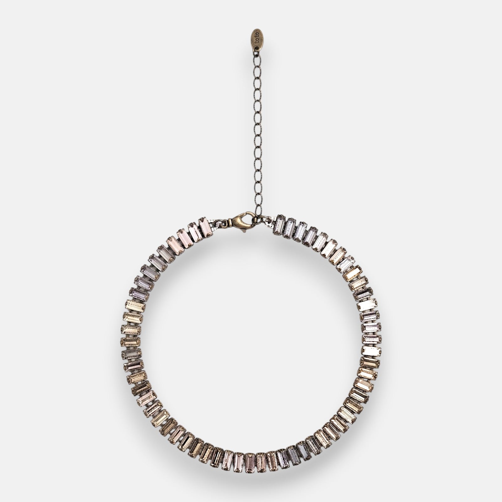 Gargantilla choker Tataborello extendida en círculo mostrando su hilera continua de cristales rectangulares rosa nude y gris ahumado.