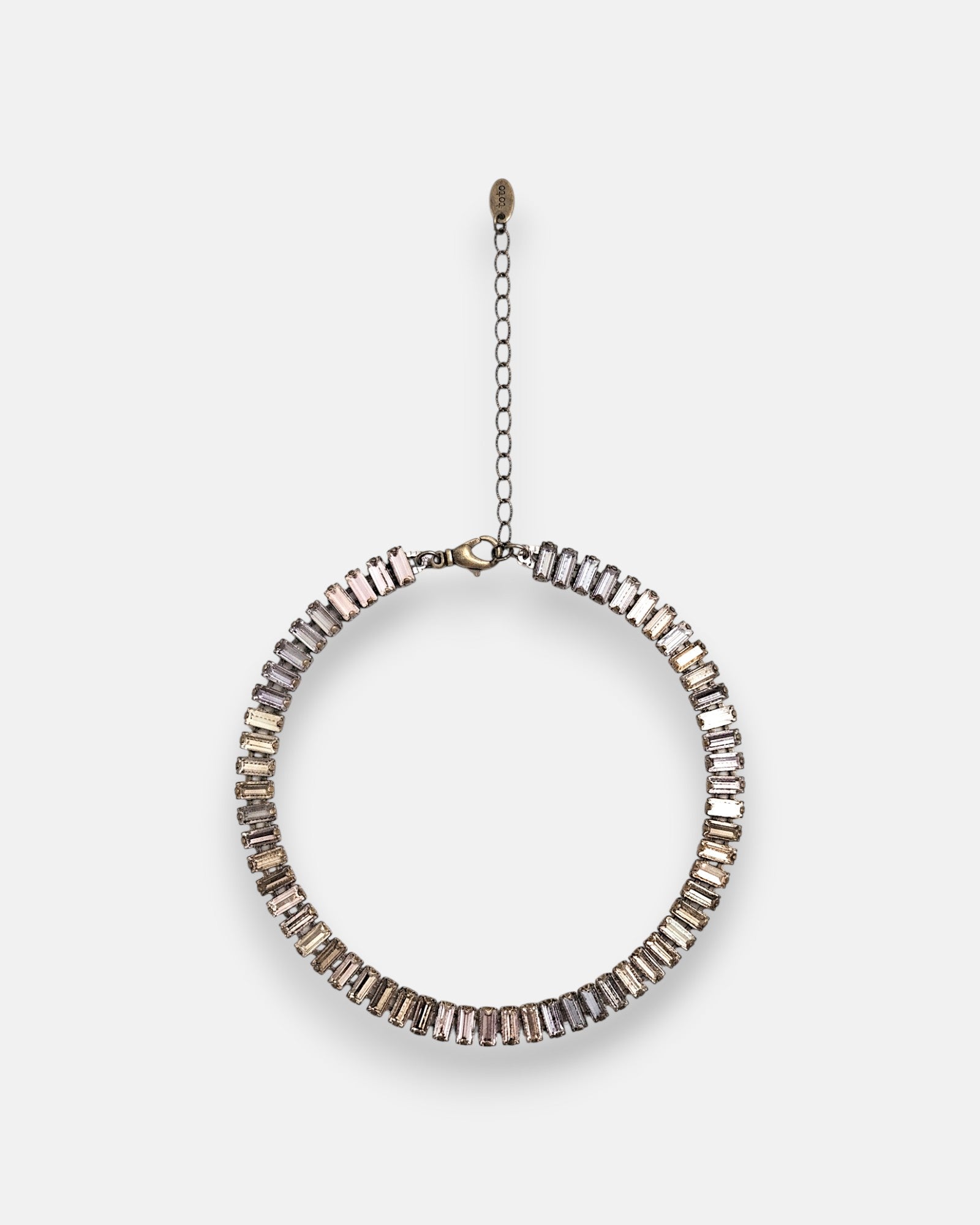 Gargantilla choker Tataborello extendida en círculo mostrando su hilera continua de cristales rectangulares rosa nude y gris ahumado.
