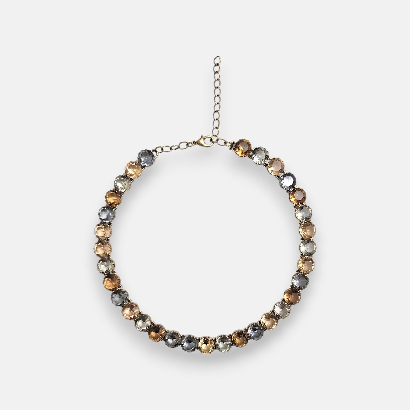 Collar corto estilo rivière de Tataborello extendido en círculo mostrando su hilera continua de cristales redondos facetados en tonos ahumados y ámbar con cierre de mosquetón.
